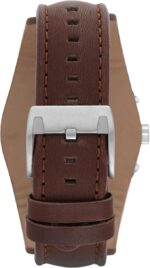 Close-up of a brown leather watch strap with a silver tang buckle and stitched edges.