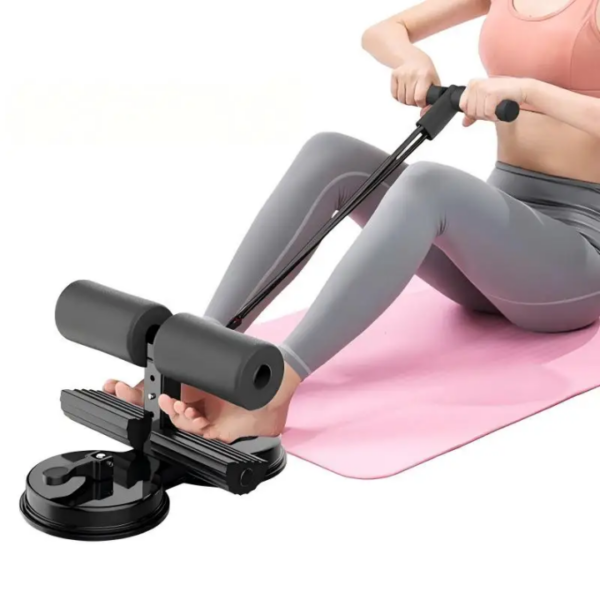 Compact pedal exerciser with foam rollers and suction base, being used on a pink exercise mat for leg/arm workouts.