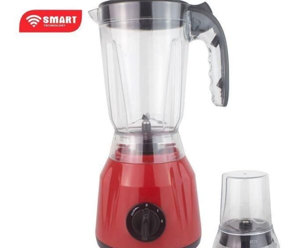 Red countertop blender with a clear glass pitcher and lid, and a separate small grinding attachment beside it.