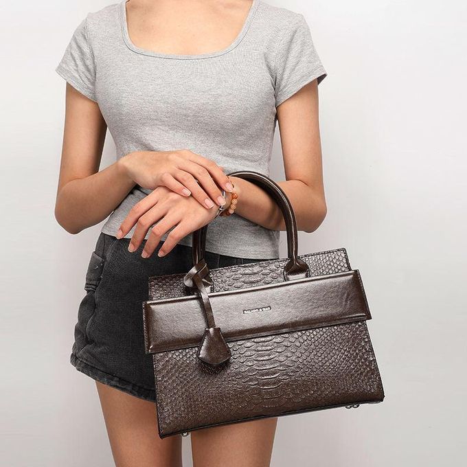 1 (4) Person wearing a gray top and black shorts holding a dark brown textured handbag with top handles and a small front flap pocket nearby.
