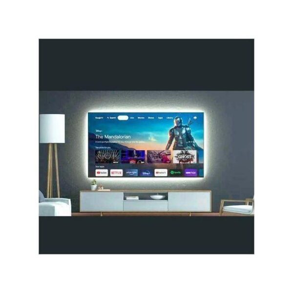 Living room with a large flat-screen TV on a console, glowing on a dark wall and surrounded by a lamp and seating area.