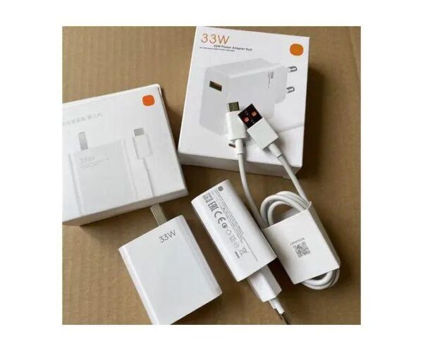 White 33W USB-C power adapter kit with cable and packaging on a cardboard surface, unboxed and arranged neatly.