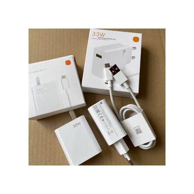 White 33W USB-C power adapter kit with cable and packaging on a cardboard surface, unboxed and arranged neatly.