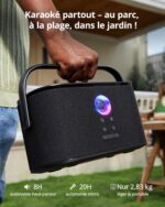 Close-up of a person carrying a black portable speaker outdoors; the speaker has a blue-purple ring light and there is white French text overlaid: 'Karaoké partout – au parc, à la plage, dans le jardin !'